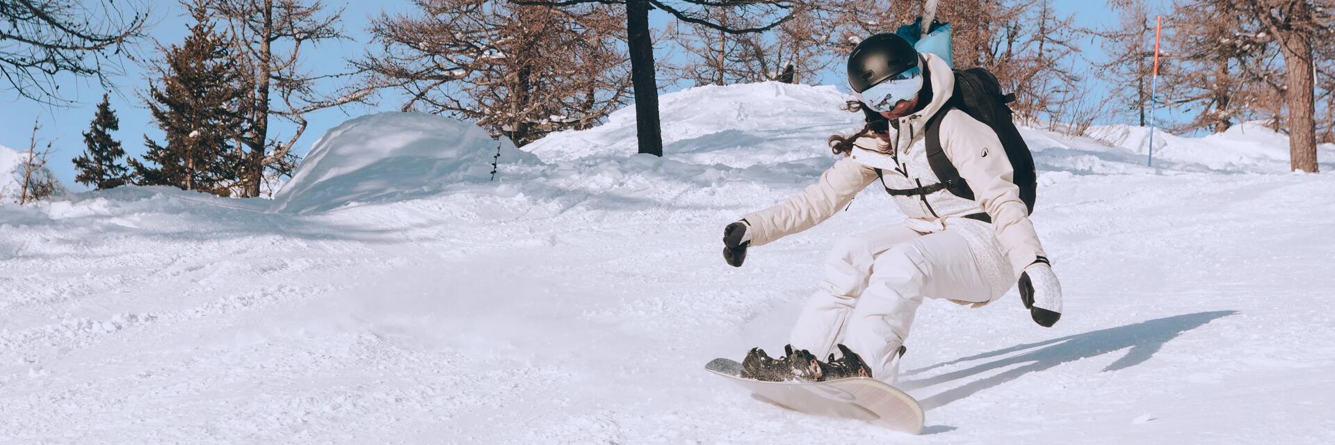 Kobieta w odzieży zimowej i w kasku jeżdżąca na snowboardzie