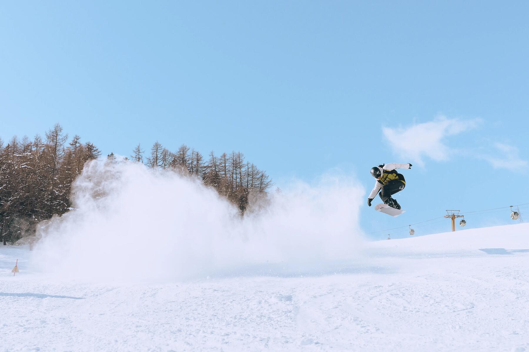 Mężczyzna w kasku i w goglach trenujący triki na snowboardzie