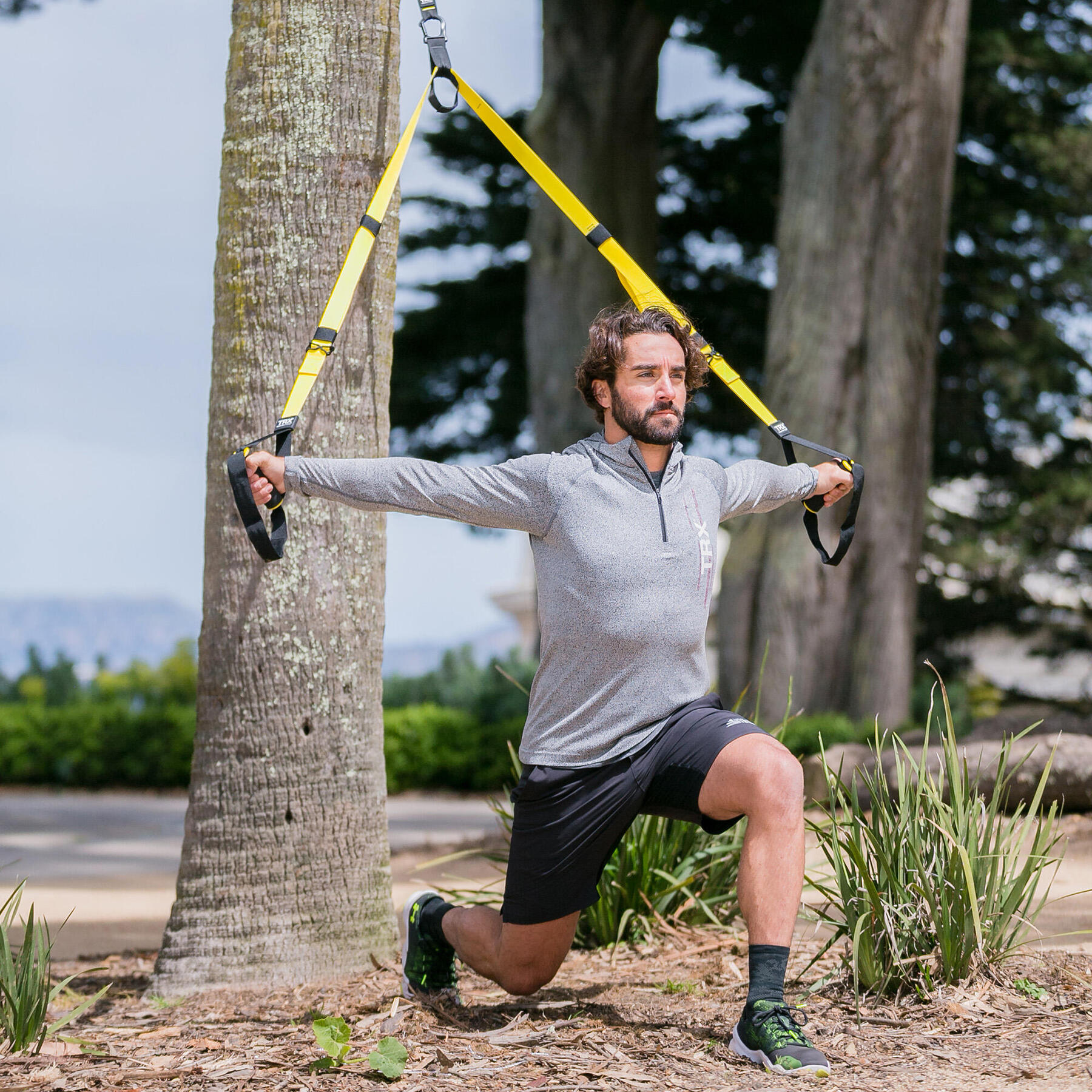 jovem a fazer exercicio com correias de suspensao no exterior