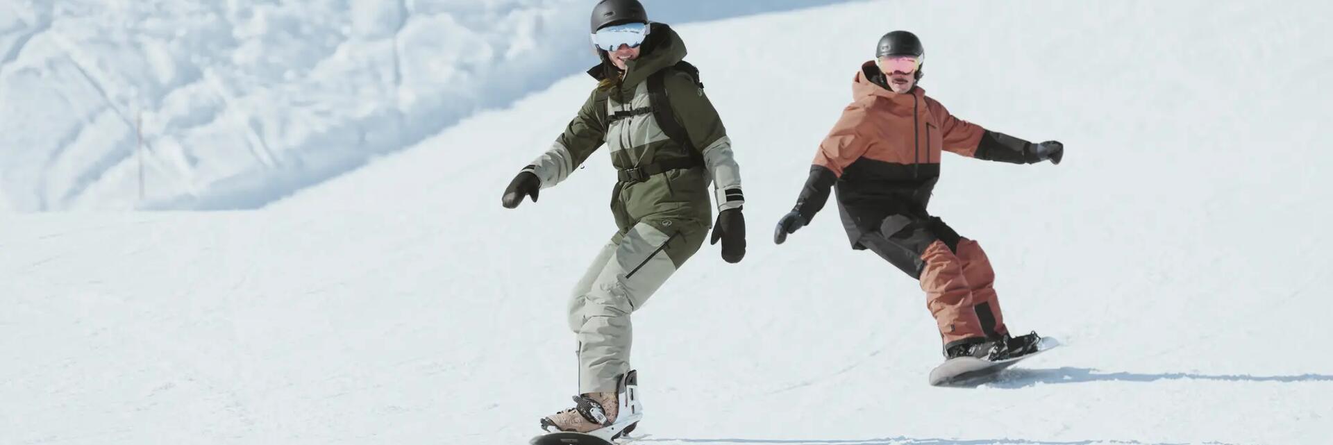 Dwie osoby w kasku i w goglach jeżdżące na snowboardzie