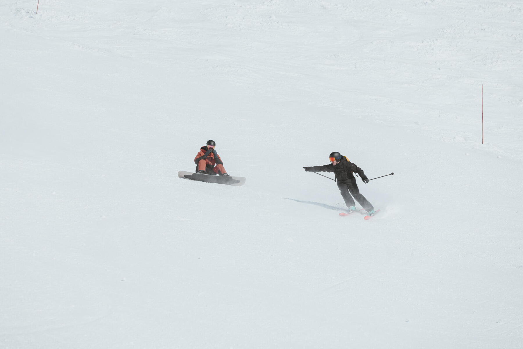 Ludzie na stoku jeden na nartach drugi na desce snowboardowej