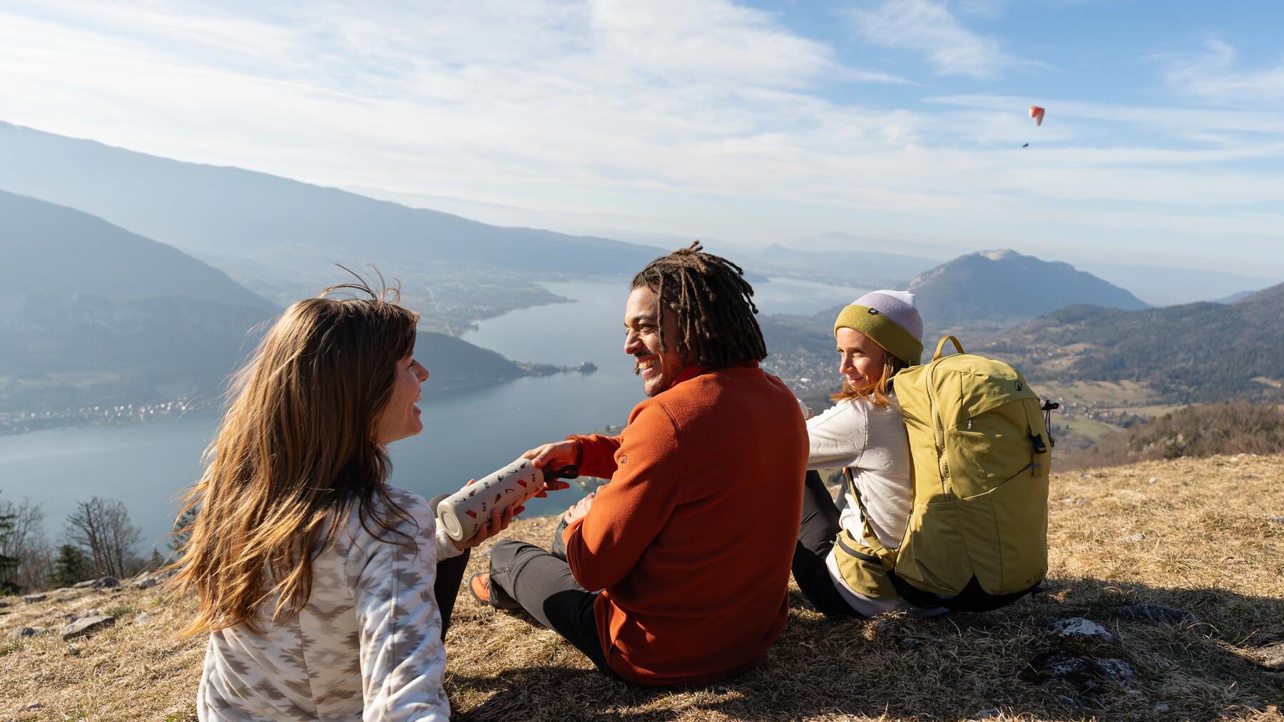 une femme souriante sous la pluie en randonnée avec son manteau jaune