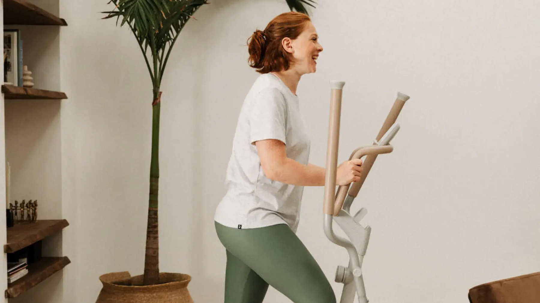 Eine Frau steht auf dem Crosstrainer im Wohnzimmer