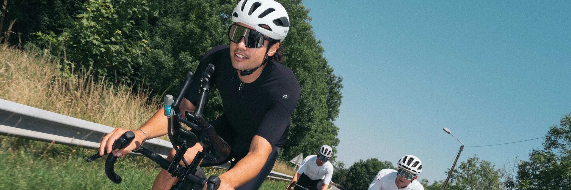 Mężczyźni jadący rowerami w kaskach i w okularach wykonujący trening tempowy