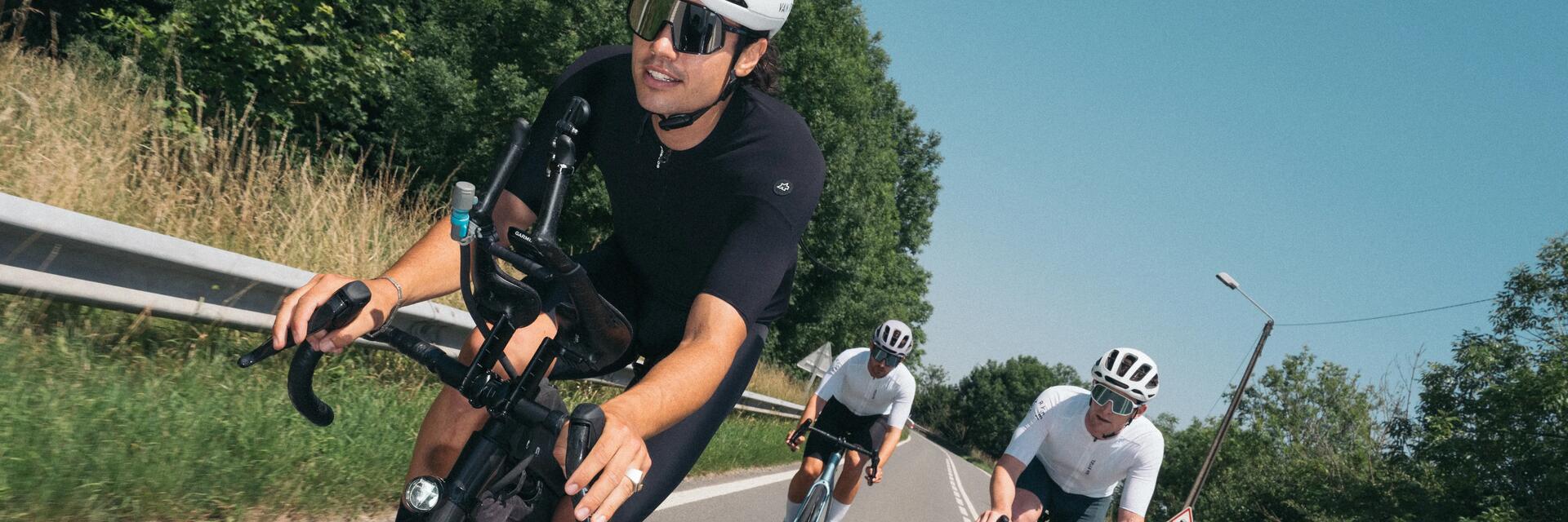 Rowerzyści w kaskach rowerowych jadący na rowerach szosowych wyposażonych w opony do szosy