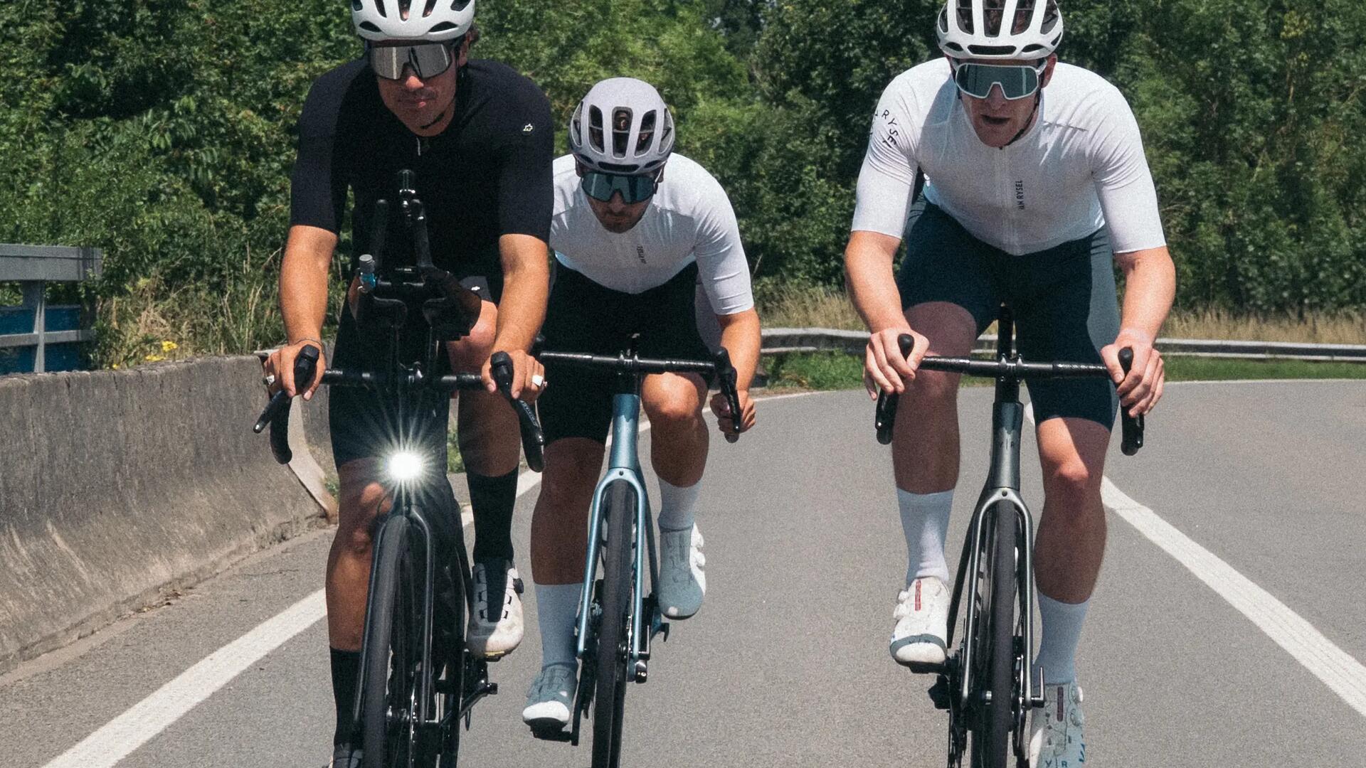 Troje ludzi na rowerach w kaskach i okularach jadący po drodze