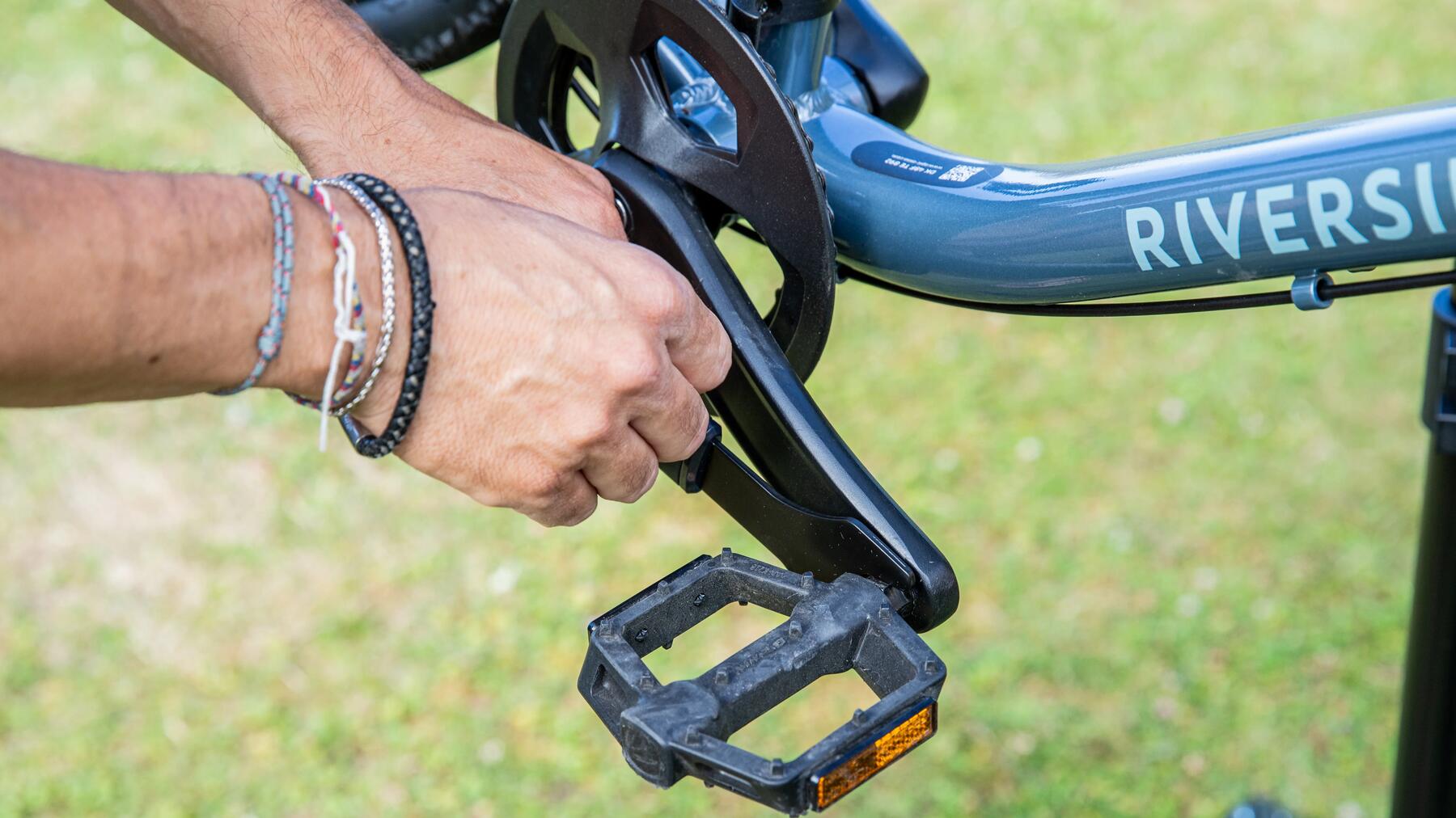 Iemand draait de rechterpedaal los op een Riverside-fiets