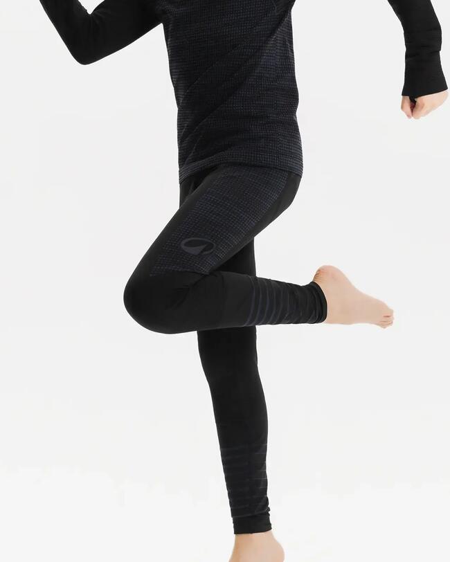 Kind bewegt sich in langem schwarzem Funktionsshirt und Funktionshose vor weißem Hintergrund. Hauptsächlich Beine zu sehen.
