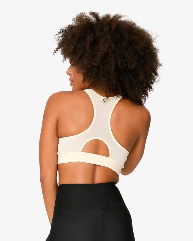 Eine Frau trägt einen Sport-BH in der Farbe beige.