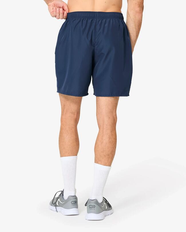 Rückenansicht eines Mannes in blauen Sportshorts, weißen Socken und grauen Sportschuhen.