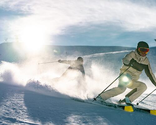 Une femme qui regarde la pente de ski avec ses lunettes sur la tête