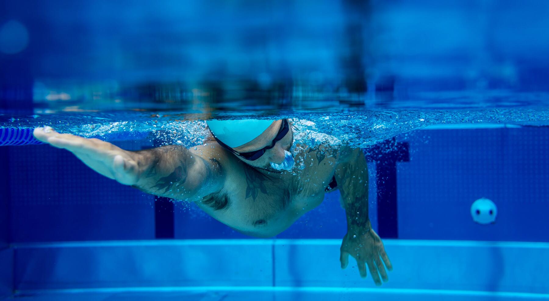 Mann krault im Schwimmbecken mit Badekappe