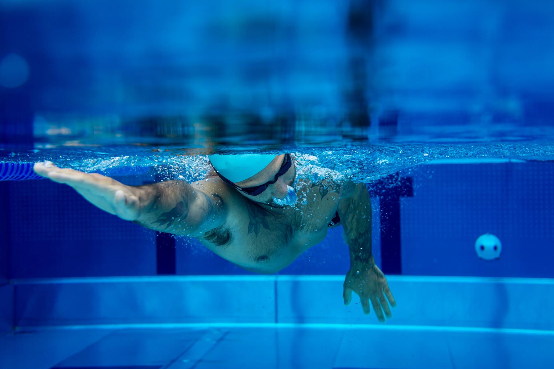 Mann krault im Schwimmbecken mit Badekappe