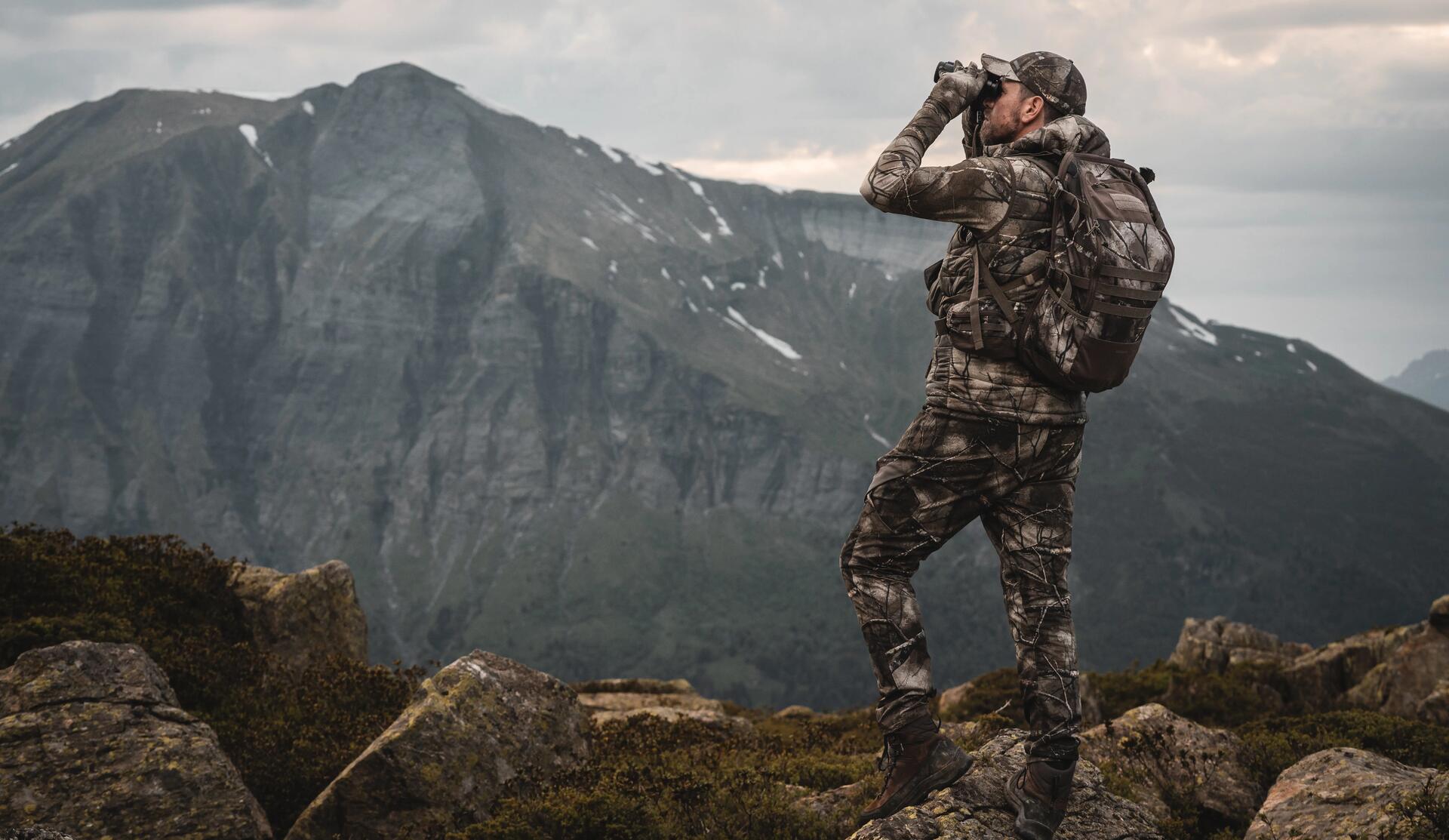 Chasseur à l'approche qui observe en montagne sur des rochers
