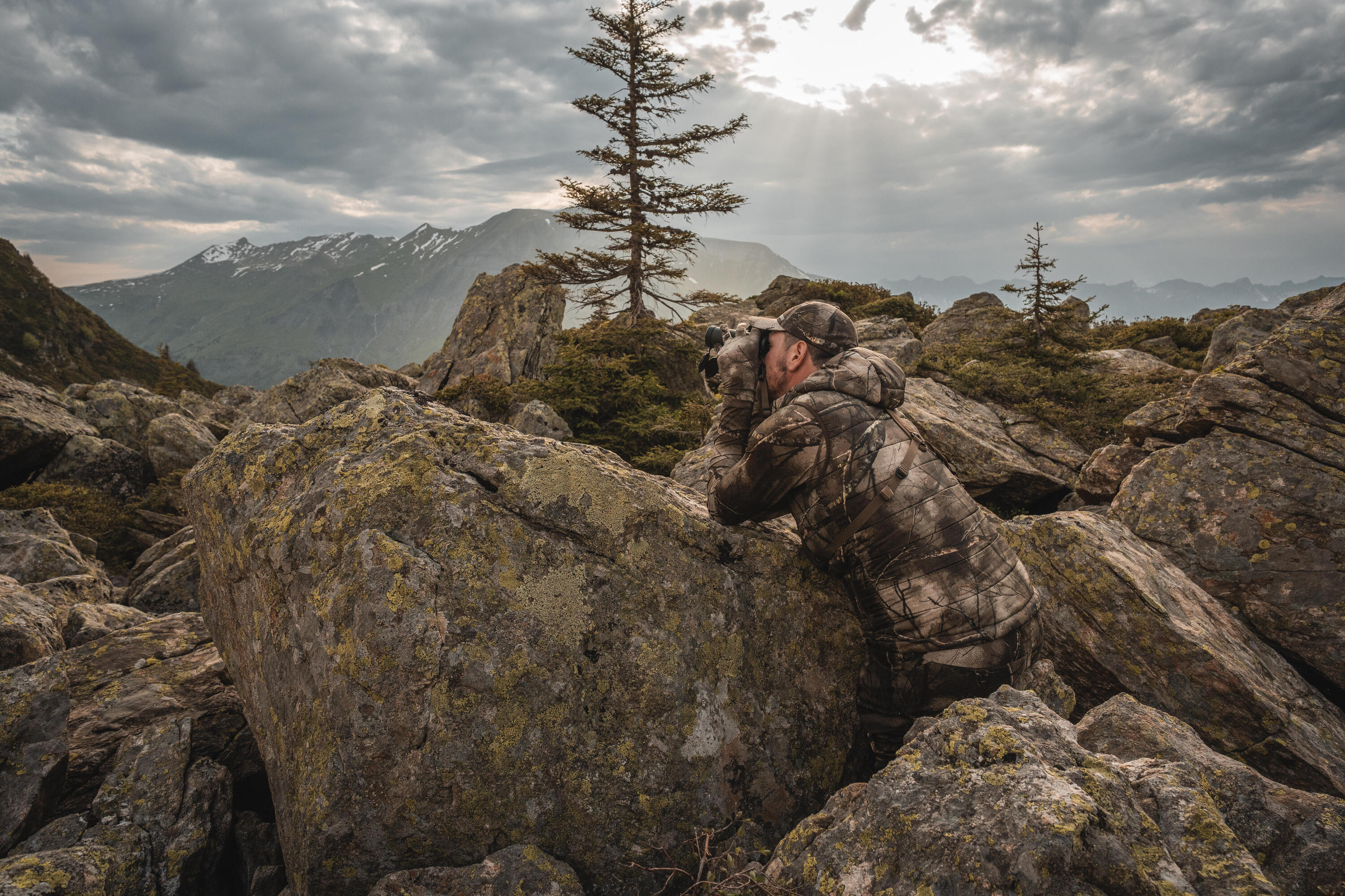 Un chasseur à l'approche avec la tenue Treemetic qui jumelle au milieu d'un environnement rocailleux
