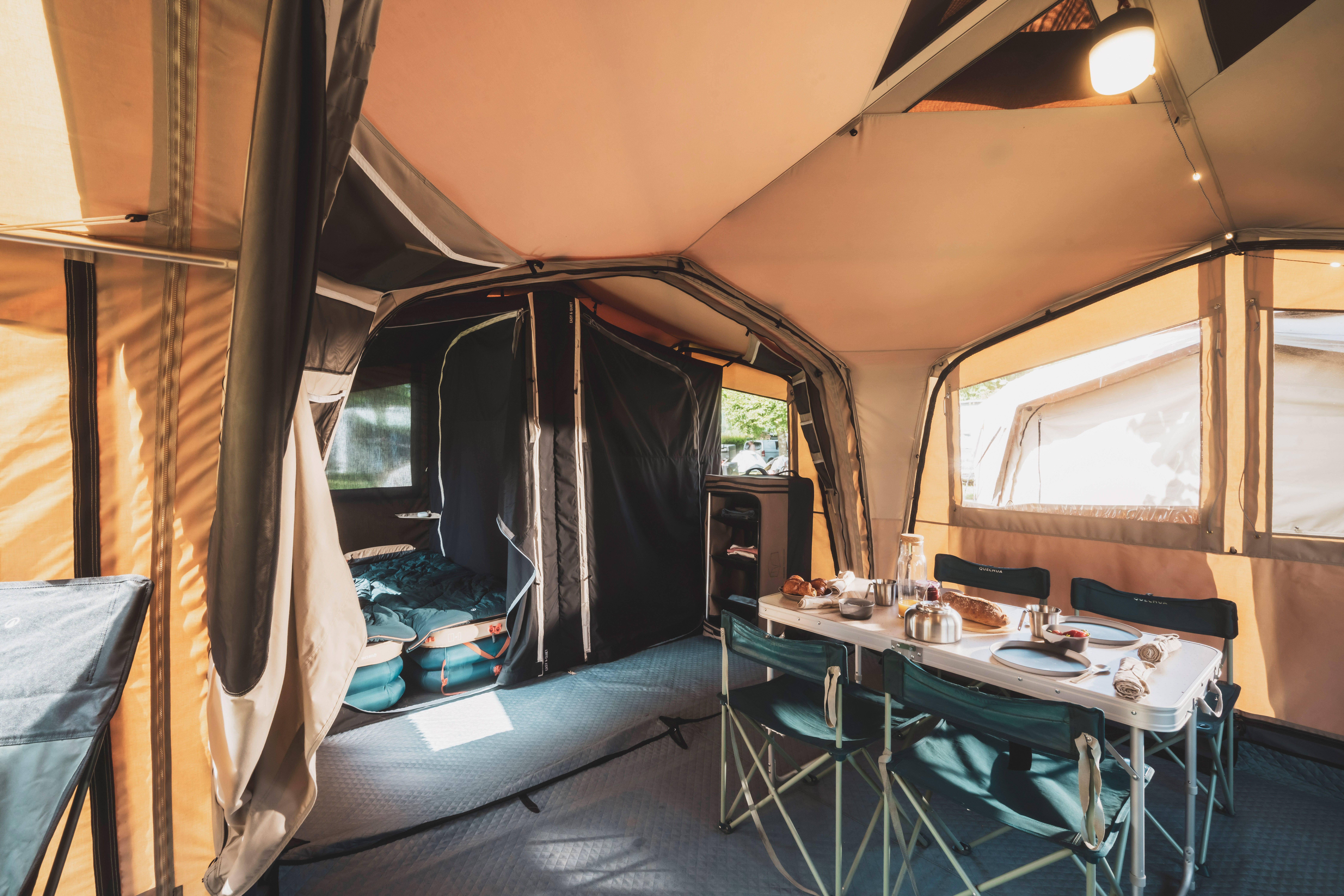 Camping table set up inside a spacious family tent with chairs and a dining setup