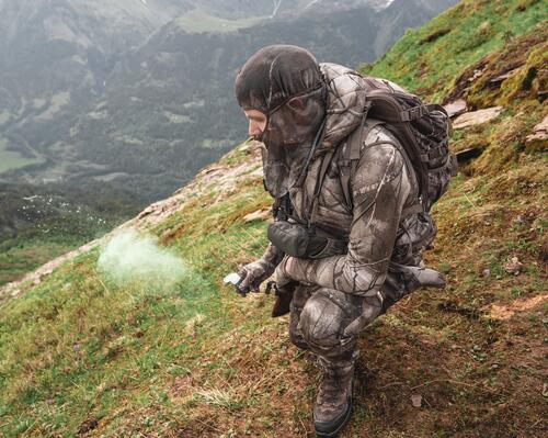 Un chasseur à l'approche utilisant une poire à vent pour connaitre le sens du vent