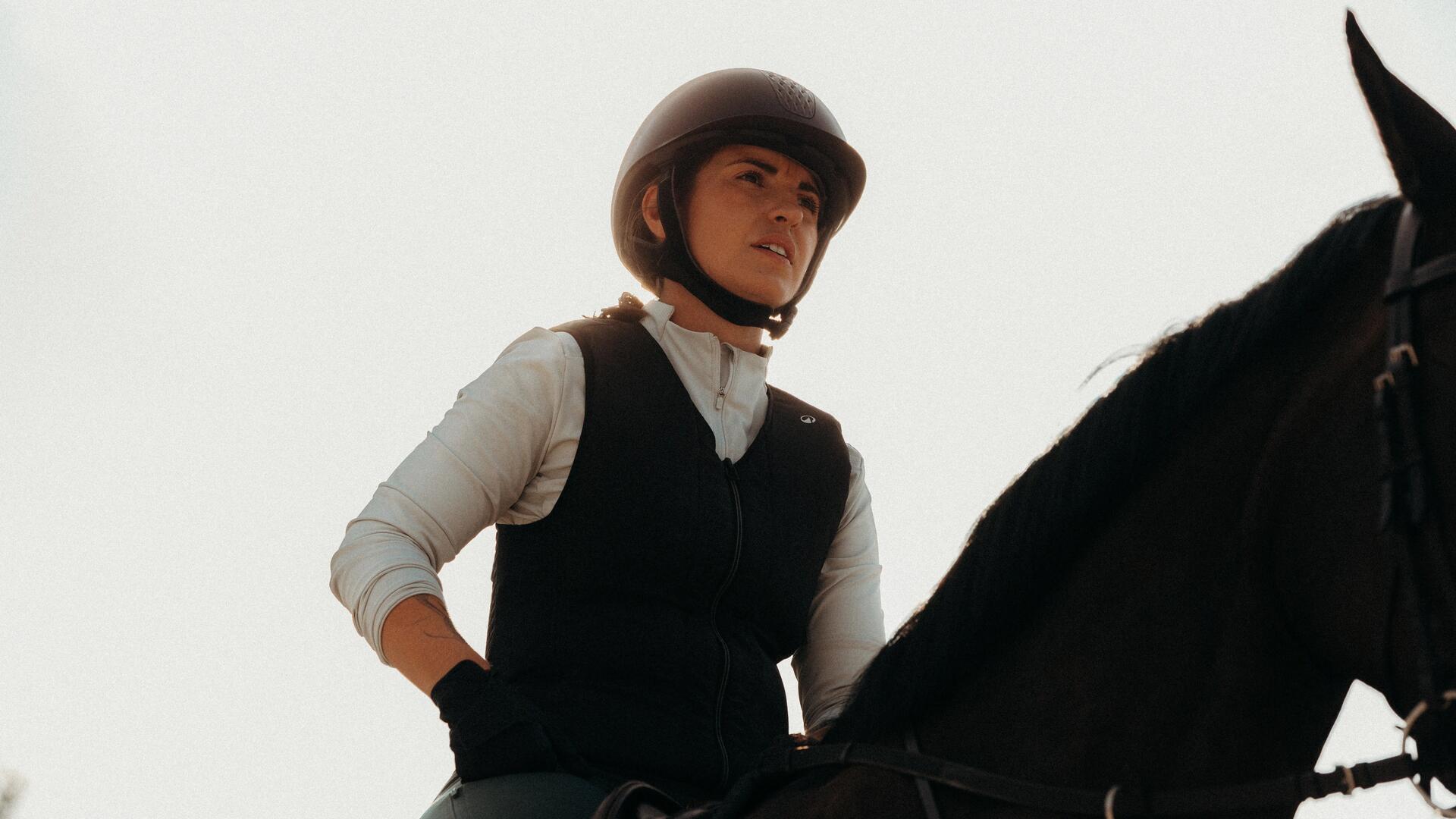 Femme qui ajuste son casque d'équitation
