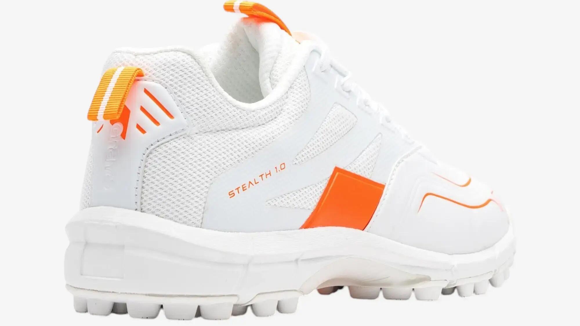Een witte veldhockeyschoen met oranje details