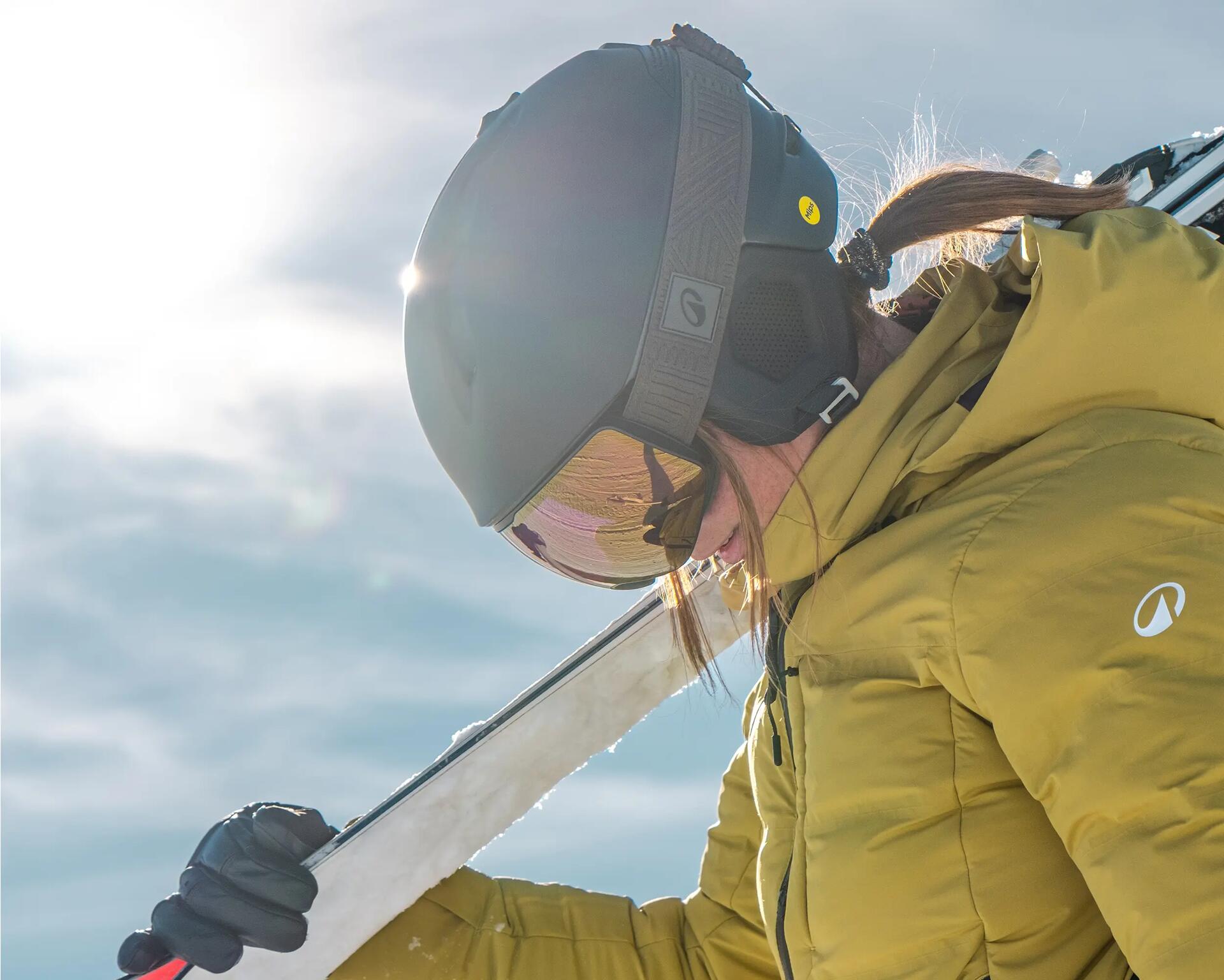 Frau mit Skihelm hält Ski