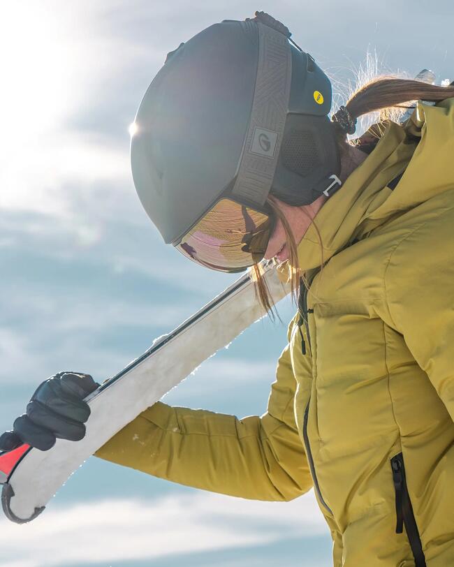 Frau mit Skihelm hält Ski