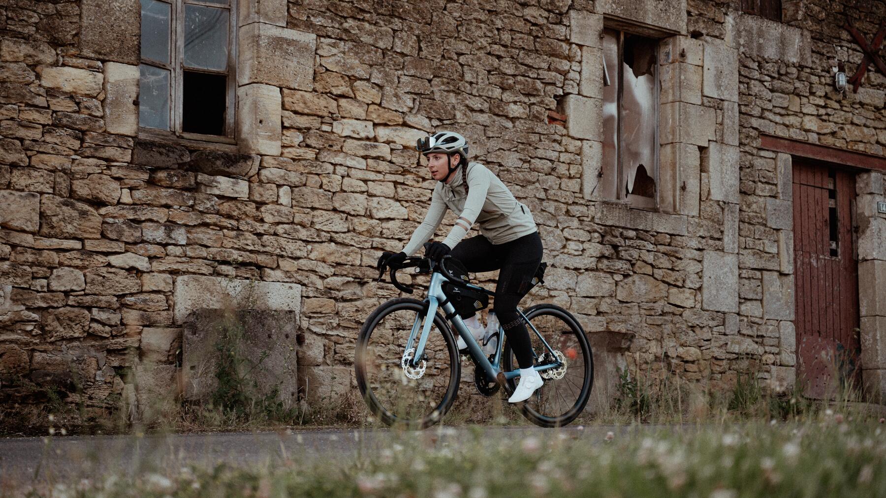 Kobieta w kasku i odzieży rowerowej jadąca na rowerze marki Van Rysel