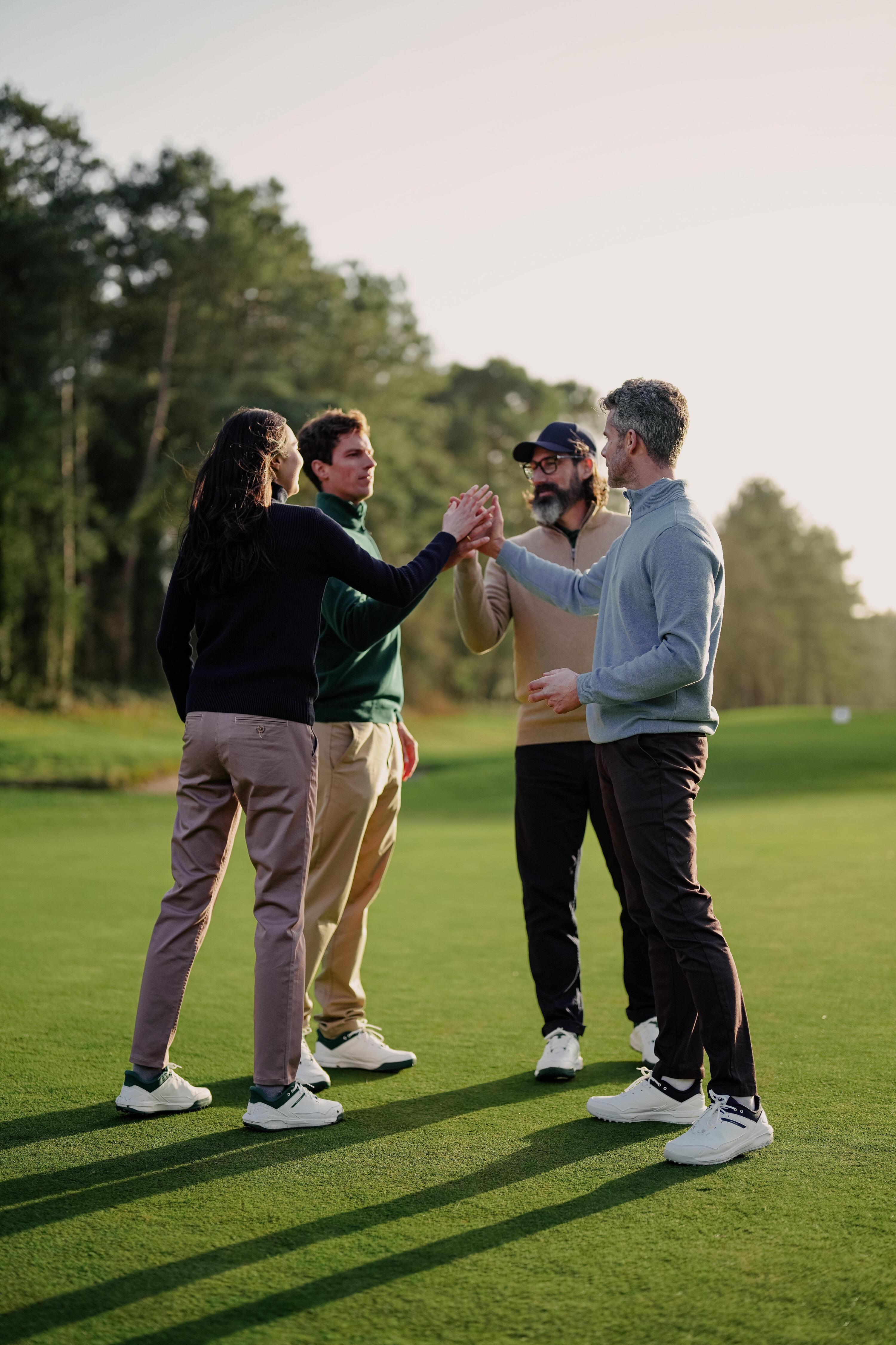 Vier Personen geben sich High Fives auf einem grünen Golfplatz.