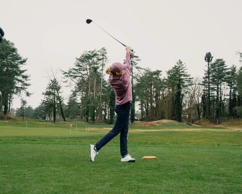 Kobieta wykonująca zmach kijem golfowym