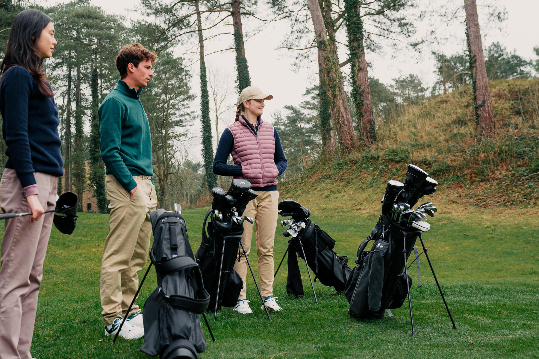 Ludzie stojący na polu golfowym obok torby z kijami golfowymi