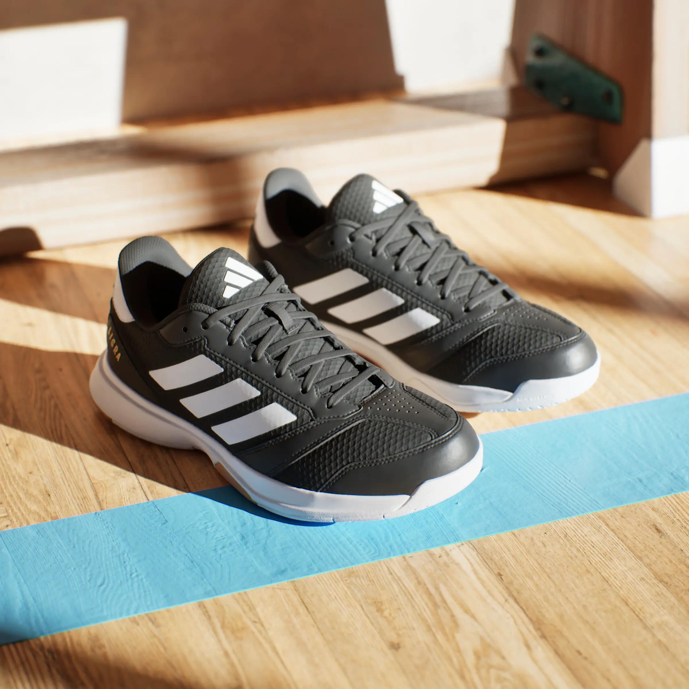 Handballschuhe adidas Ligra auf einem Hallenboden, die Schuhe hinterlassen Schatten von der Sonne.