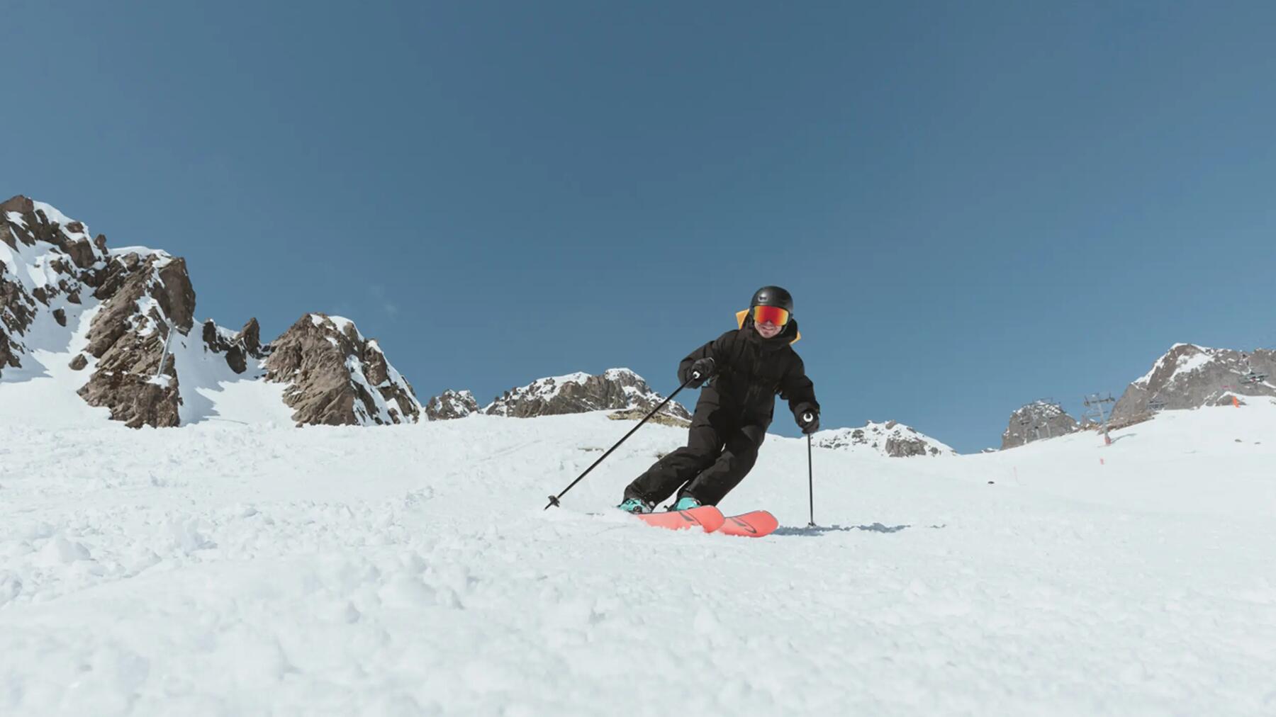 Skifahrer fährt mit Skistöcken bei blaubem Himmel