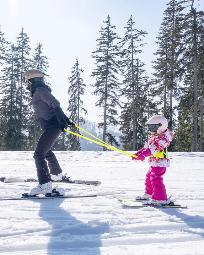 Elternteil zieht Kind auf Skiern