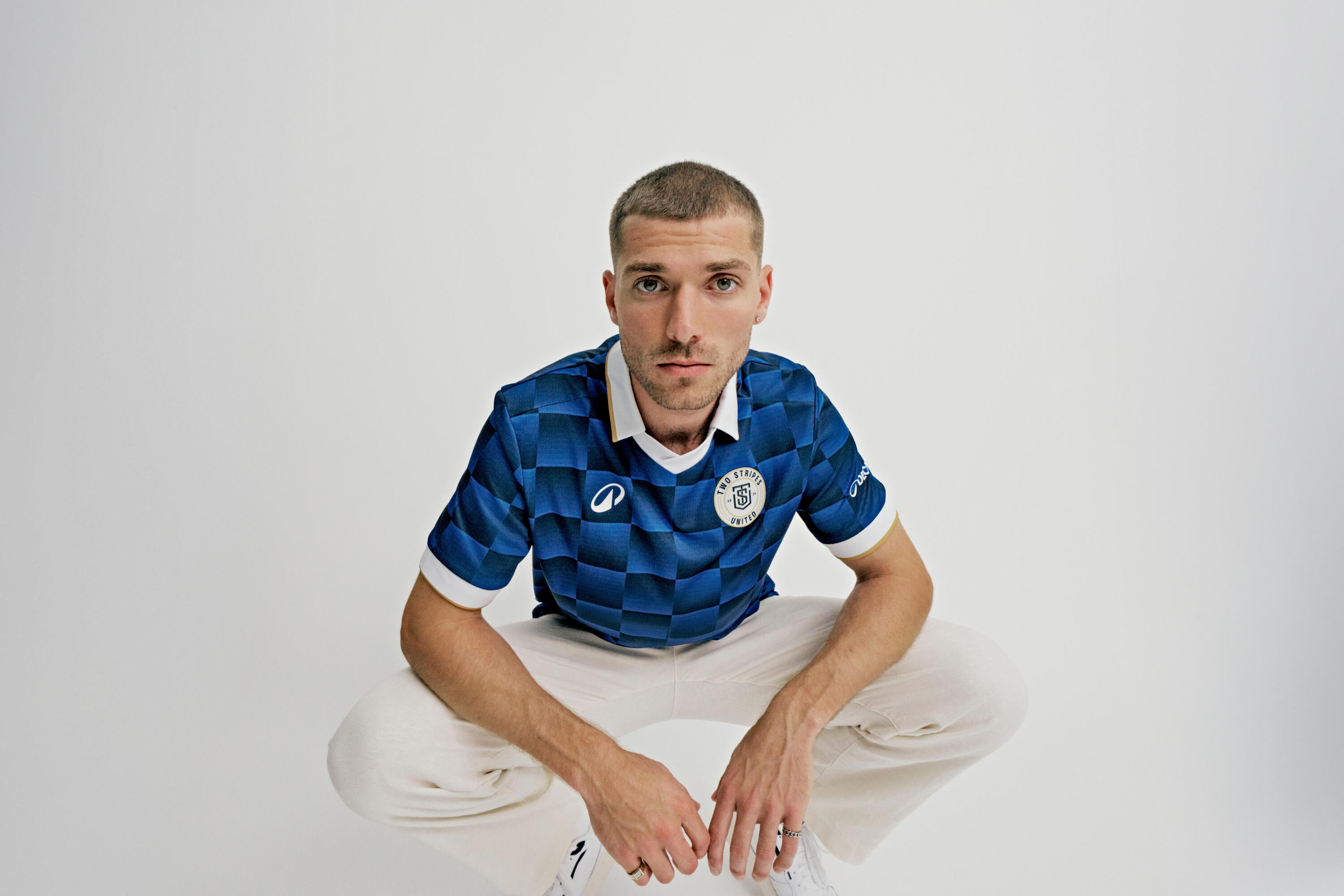 Mann hockend in Two Stripes United Heimtrikot.
