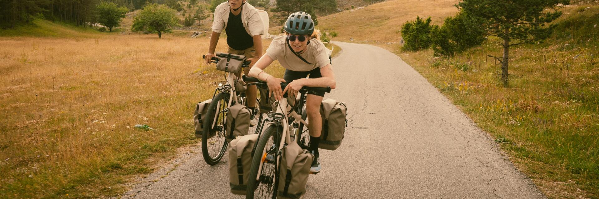 Zwei Personen fahren mit dem Fahrrad über ein Feld