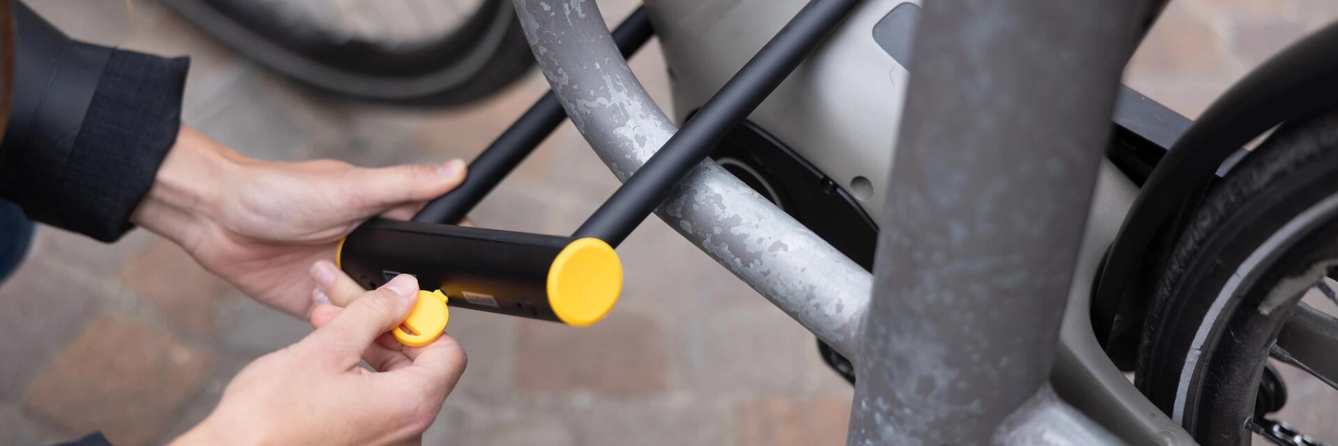 Iemand maakt een fiets vast met een U-slot (beugelslot)