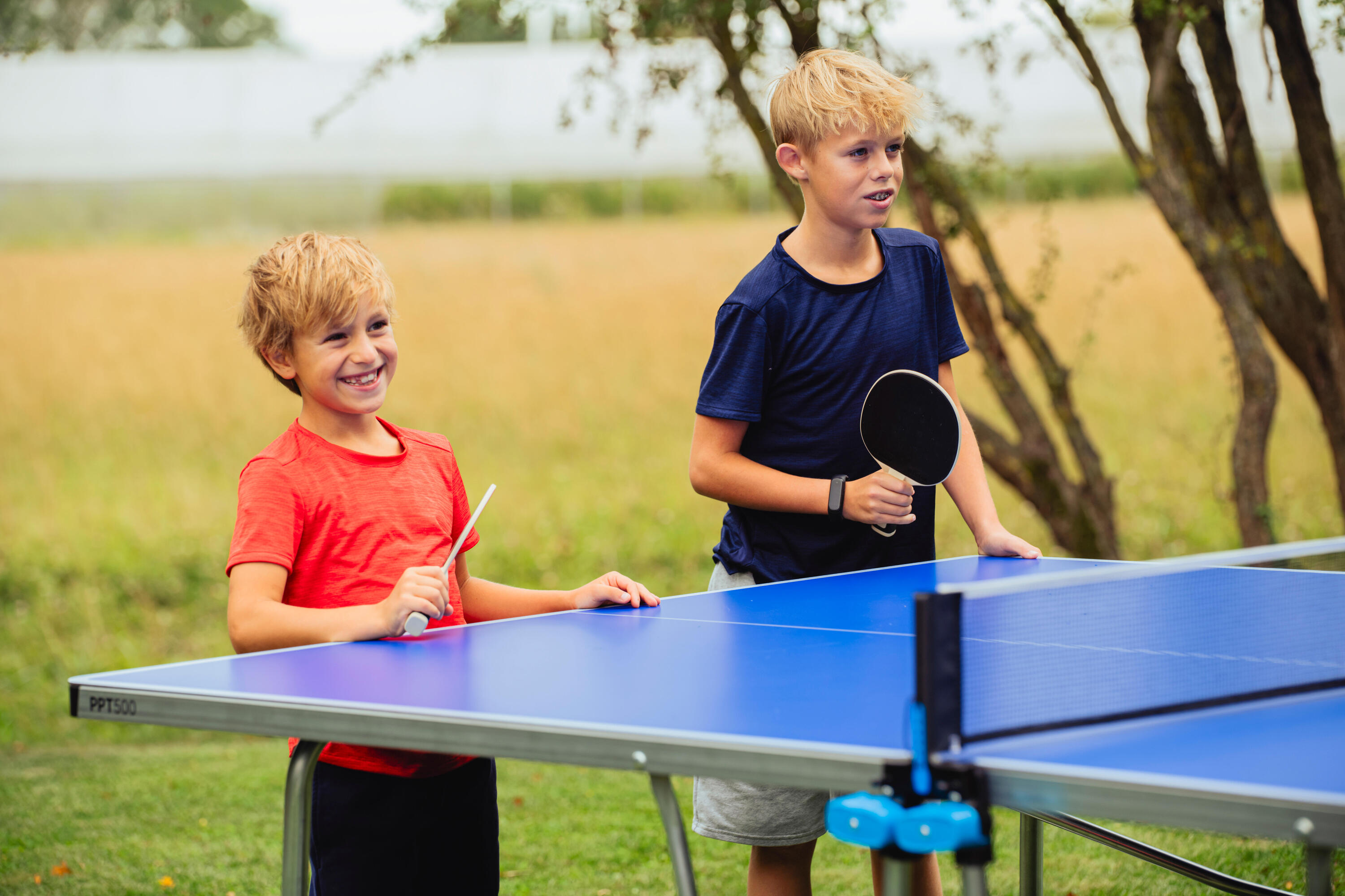 Zwei Jungen stehen an einer Tischtennisplatte mit Schlägern in der Hand.
