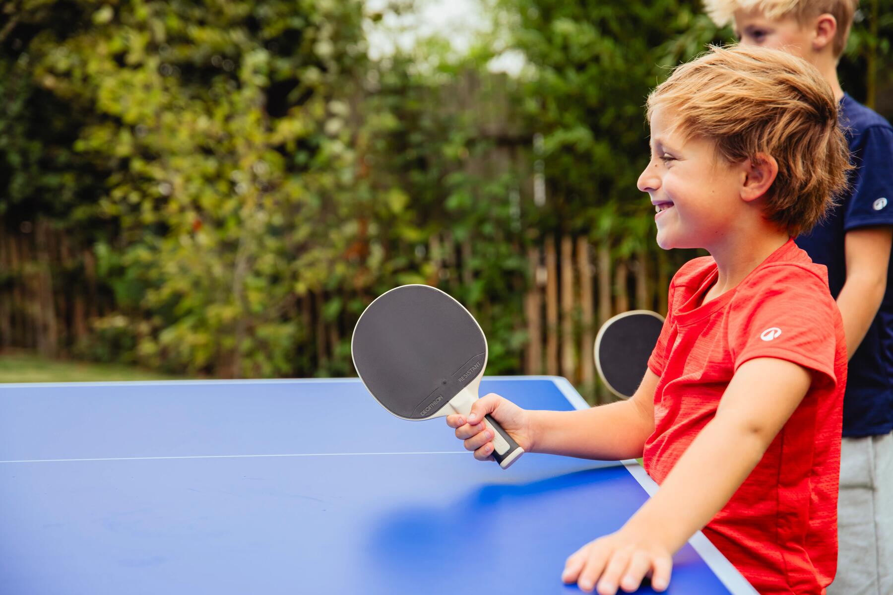 Zwei Jungs spielen im Garten mit Tischtennisschlägern