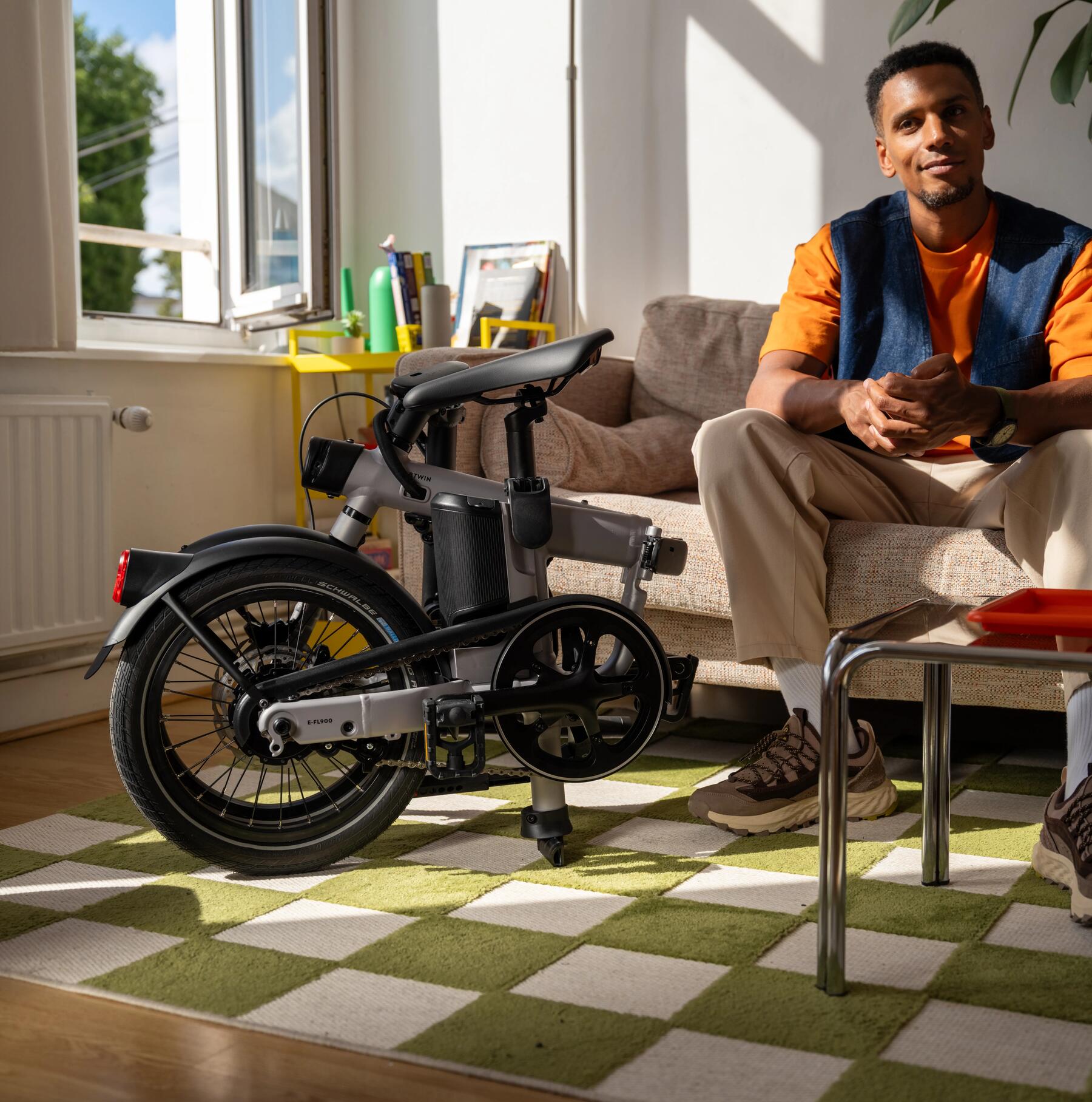 Ein Mann sitzt auf der Couch und neben ihm steht sein Klapprad