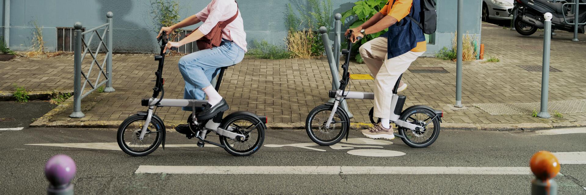 Zwei Personen fahren auf Klapprädern durch die Stadt