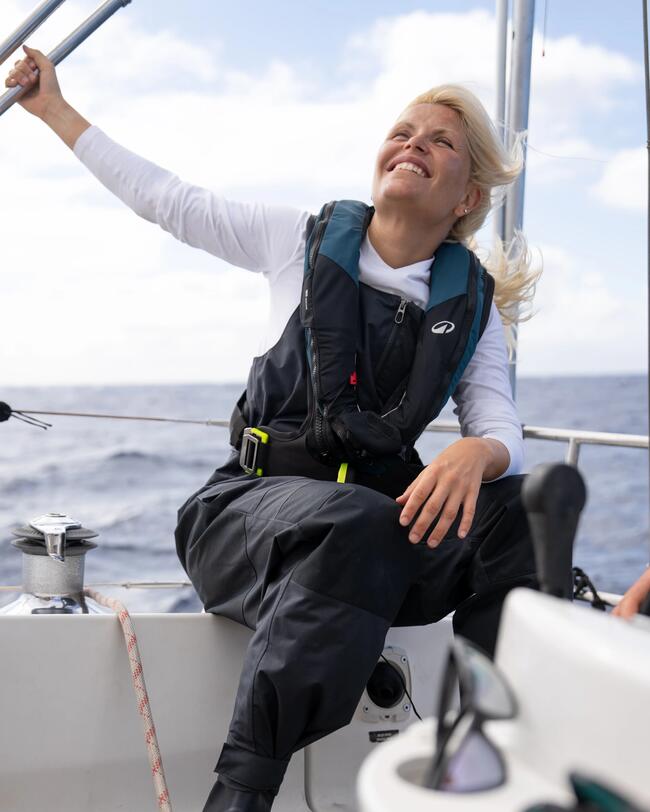 Seglerin, die im hinteren Teil des Bootes sitzt, mit einer Segel-Latzhose und einer Rettungsweste