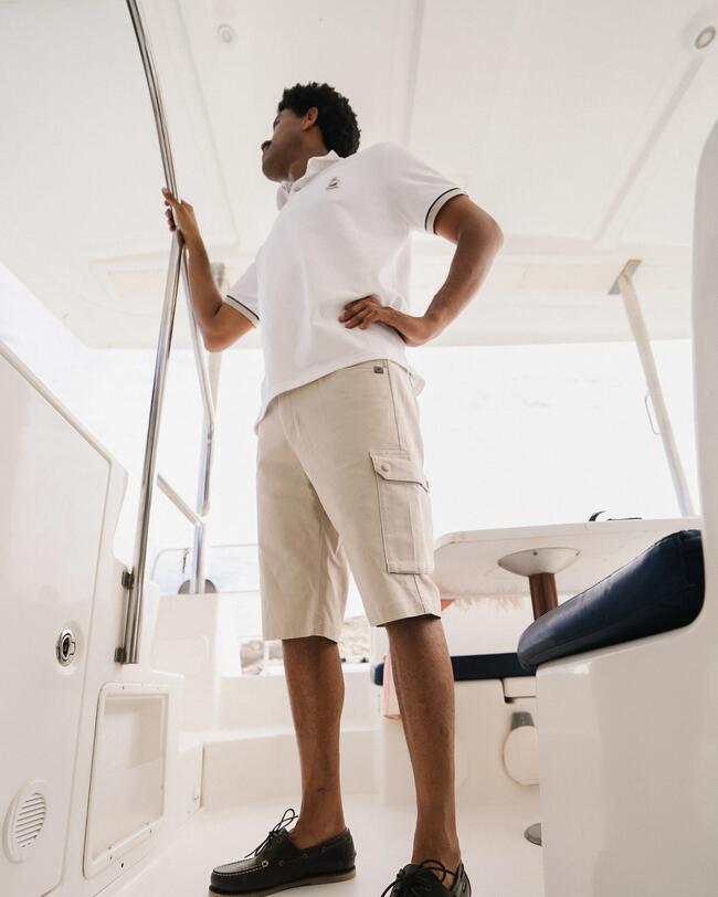 marin en short cargo et polo blanc sur un bateau