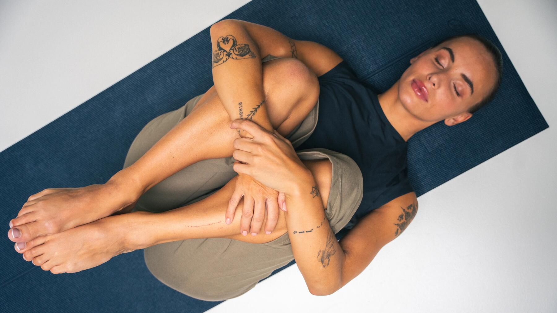 Kobieta w odzieży sportowej wykonująca ćwiczenie pilates na ból kręgosłupa leżąc na macie