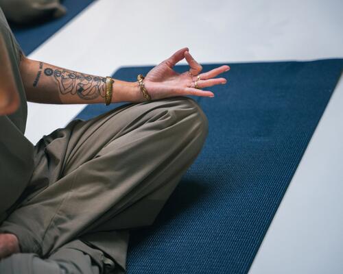 Kobieta siedząca na macie ćwicząca jogę kundalini