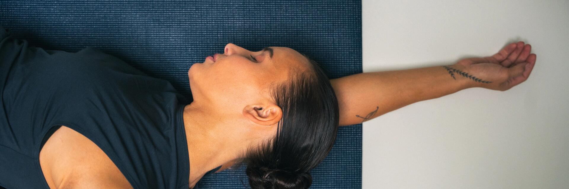 Nahaufnahme einer Frau liegend auf blauer Yogamatte beim Hormonyoga