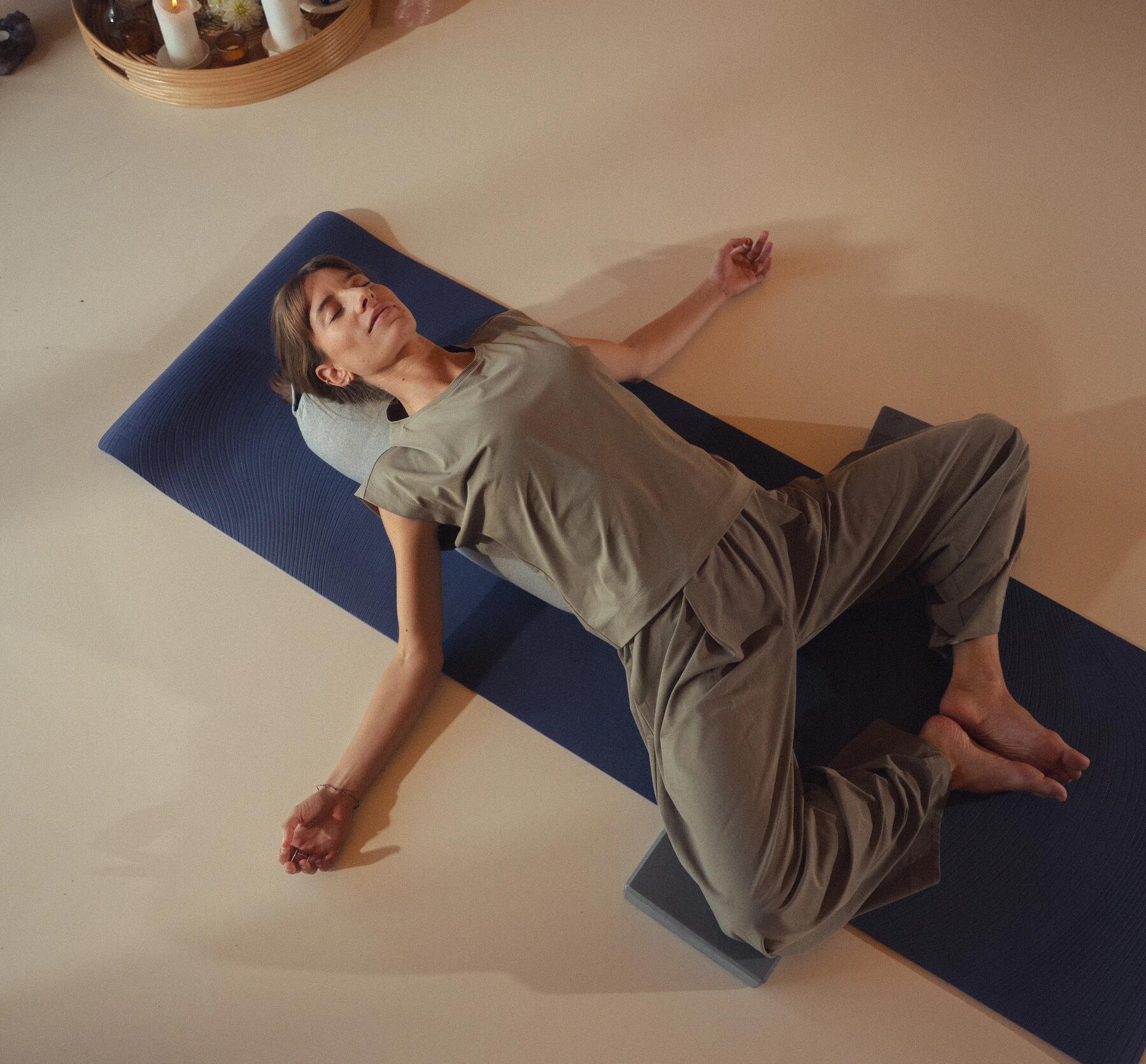 Eine Frau liegt mit dem Rücken auf einer Yogarolle