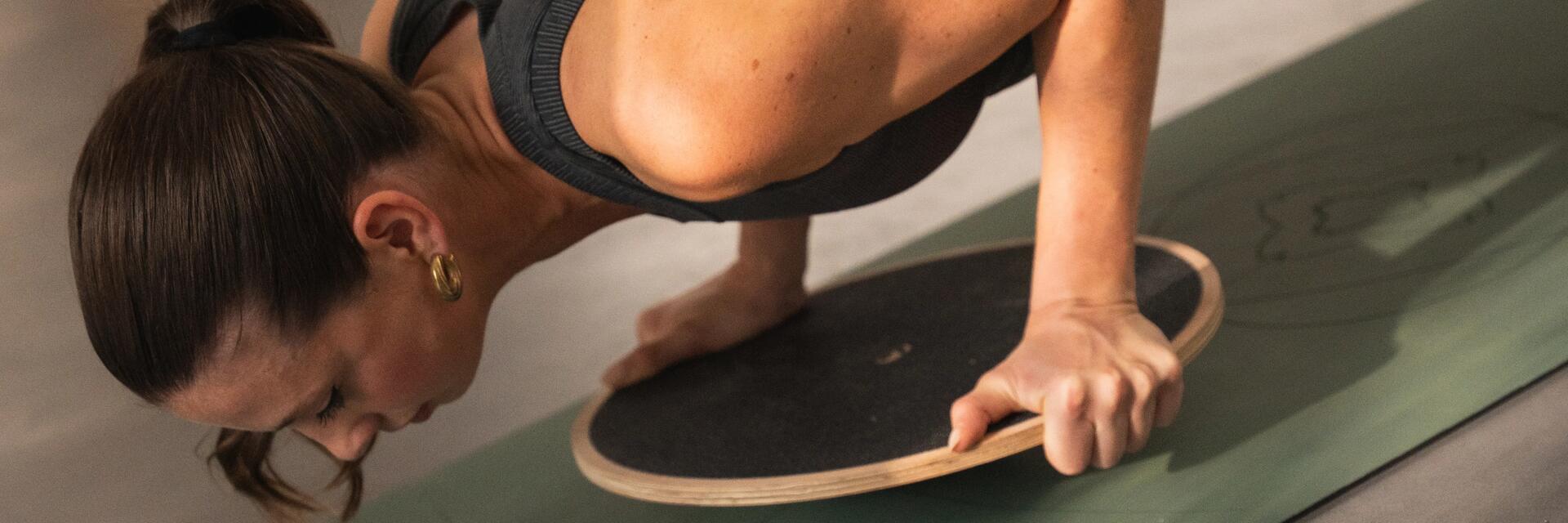 Frau beim intensiven Yoga auf ihrer Yogamatte in schwarzem Sportoberteil