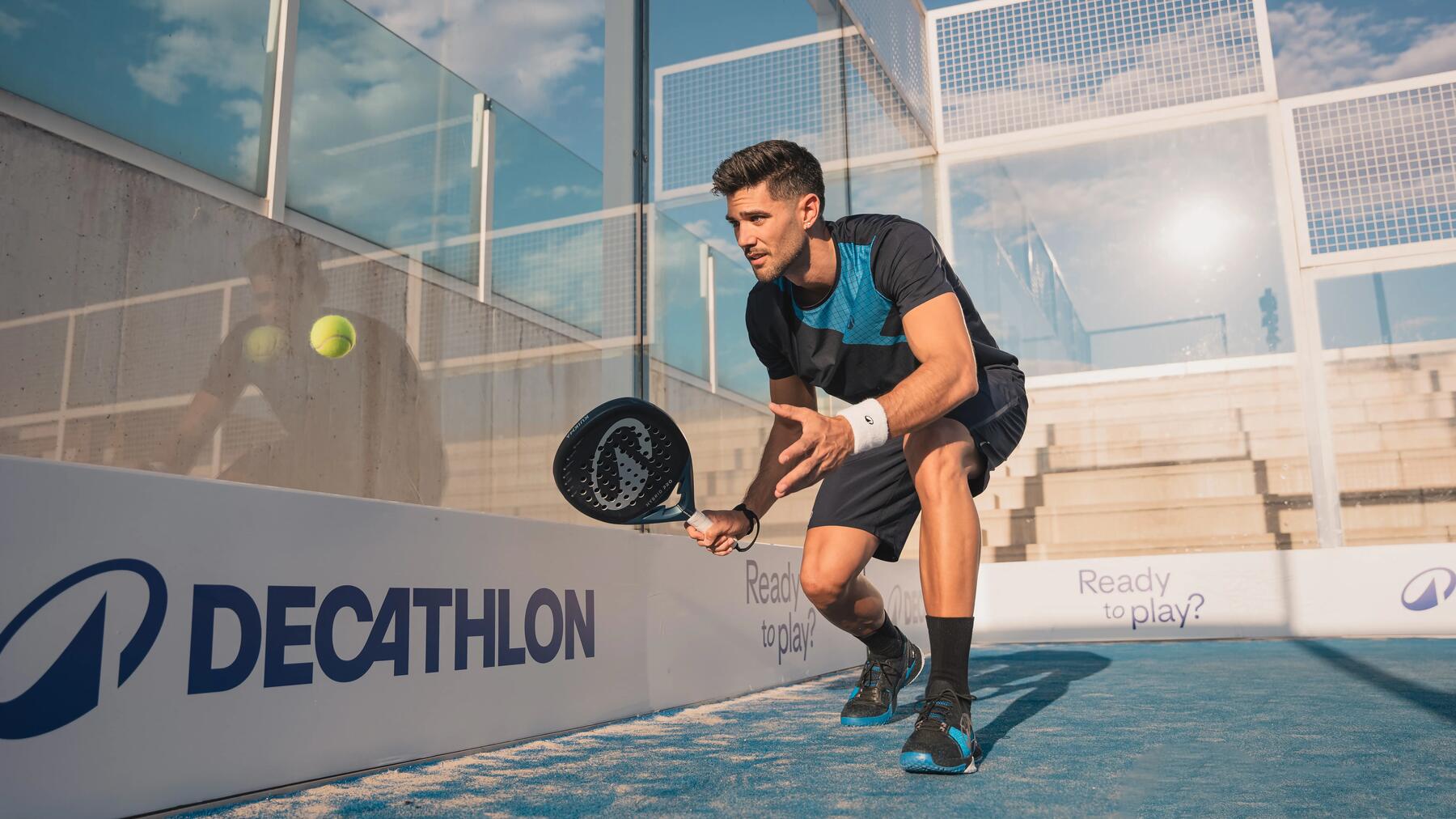 Ein Padelspieler auf dem Court schlägt den Ball nach dem Abprallen von der Glaswand