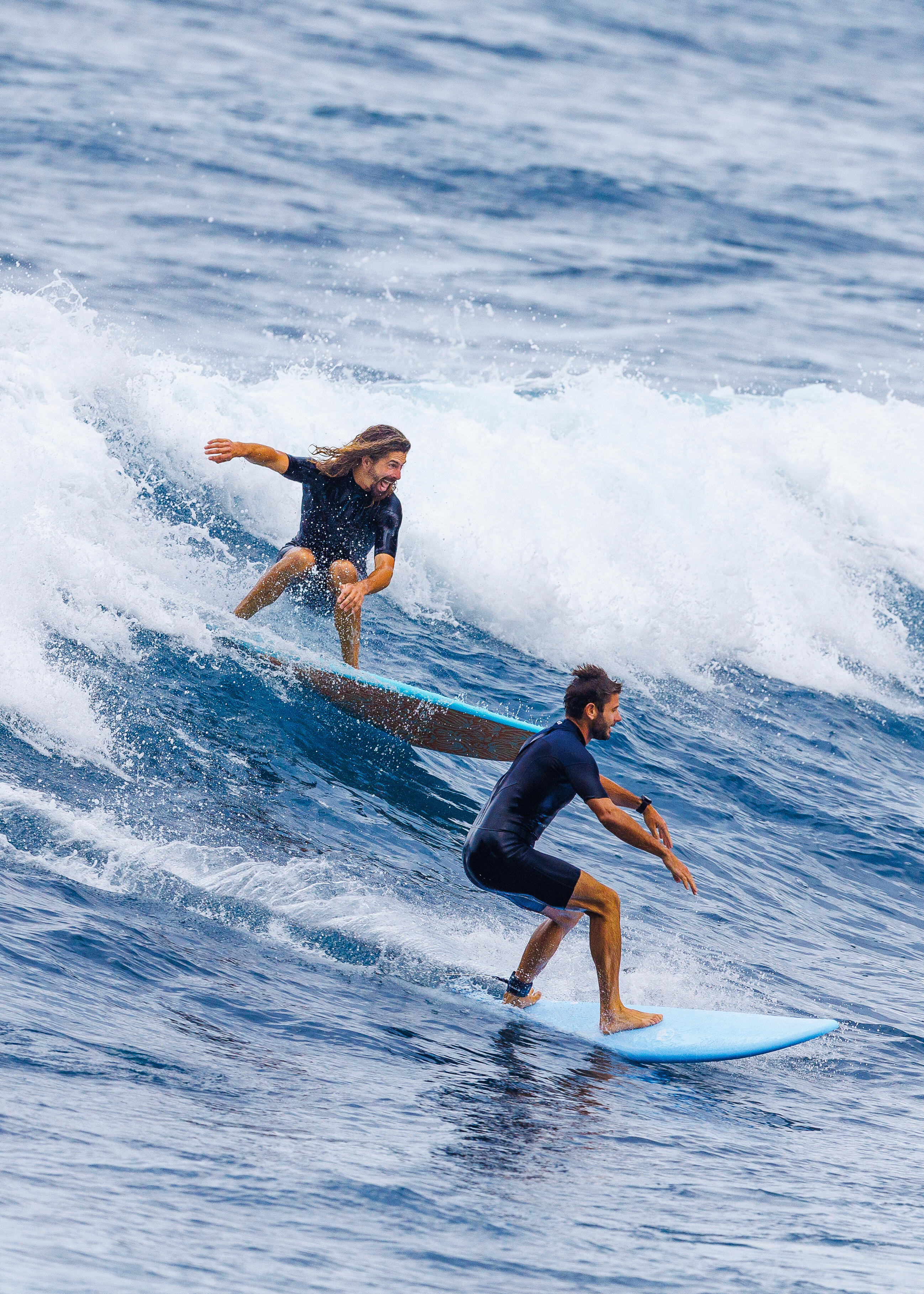 Zwei Surfer im Neoprenanzug auf der Welle