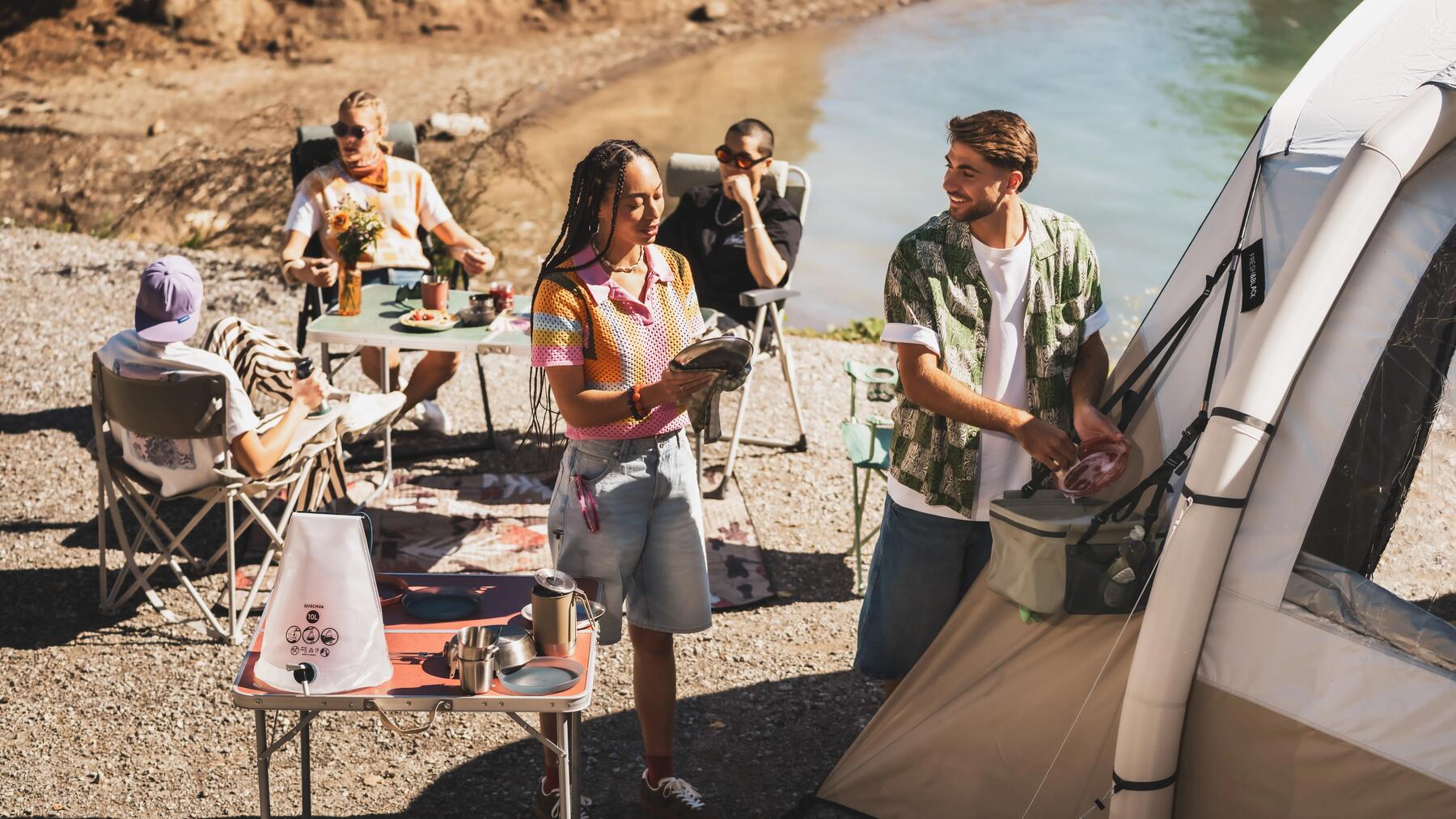 Eine Freundesgruppe spült Campinggeschirr vor dem Zelt am See