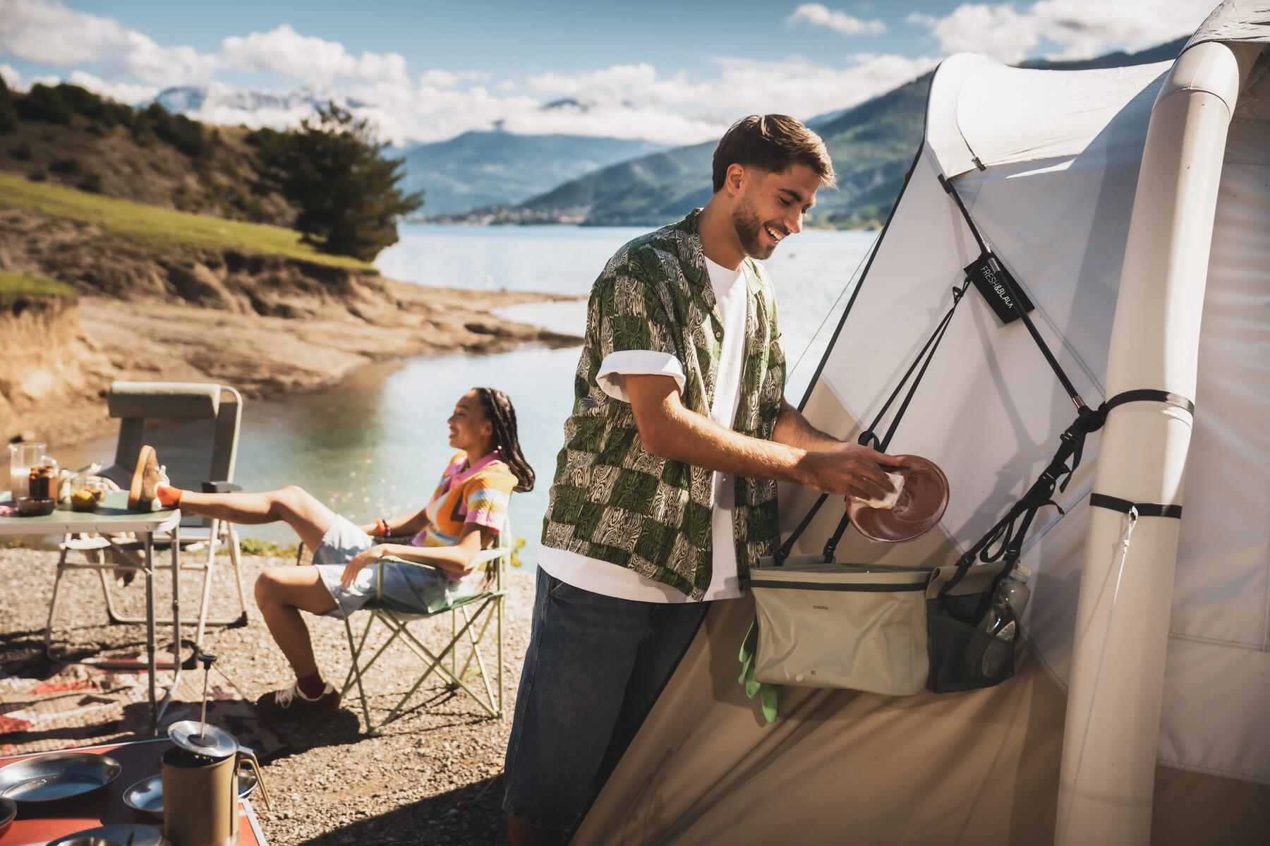 Ein Mann spült Campinggeschirr vor seinem Zelt